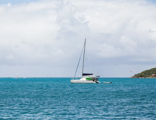 Белая парусная лодка под мачтой на голубой воде — стоковое фото