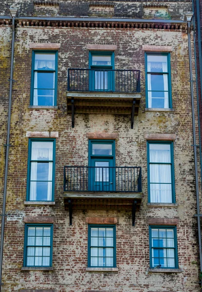 Portas verdes e varandas no edifício de tijolo velho — Fotografia de Stock