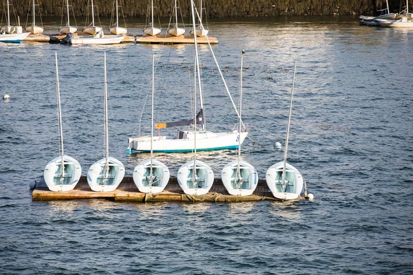 Шість вітрильних човнів на доці з одним у воді — стокове фото