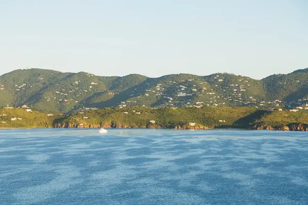 朝の光で熱帯の島に家が点在する緑の丘 — ストック写真