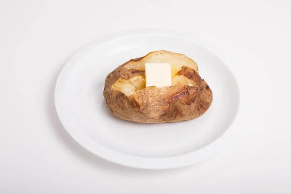 Pomme de terre au four beurrée chaude sur plaque blanche et fond — Photo