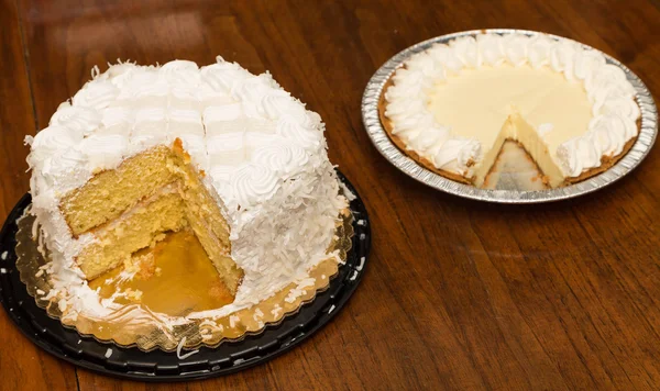 Bolo de coco cortado e torta de merengue de limão na mesa de madeira — Fotografia de Stock