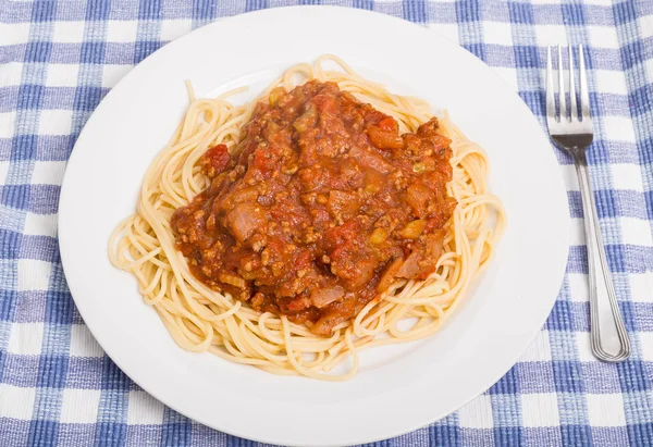 Platta av spagetti och köttfärssås på blå rutigt bordstablett — Stockfoto