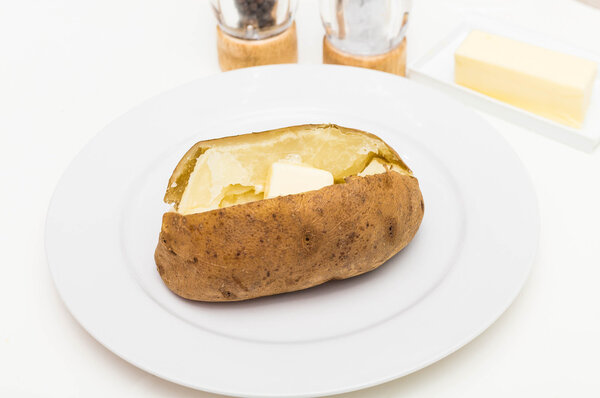 Buttered Baked Potato with Salt and Pepper in Background