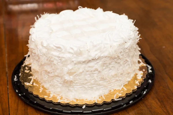 Bolo de coco inteiro na mesa de madeira — Fotografia de Stock