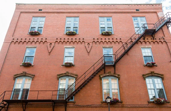 Black Iron Fire Escape Finestre passate della costruzione di mattoni — Foto Stock