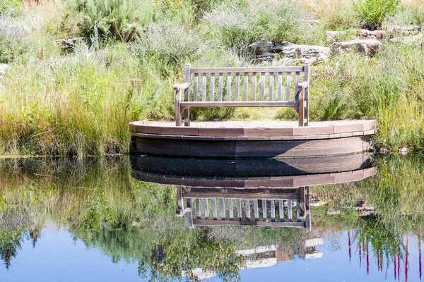 Banco en la orilla del lago con reflexión — Foto de Stock