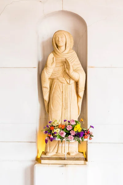 Flores bajo estatua en la iglesia — Foto de Stock