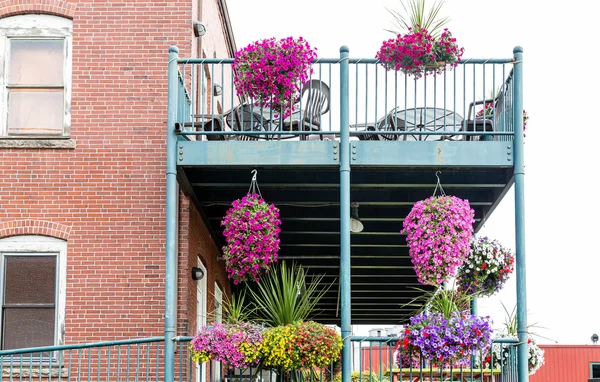 Bloemen op metalen balkon van bakstenen gebouw — Stockfoto