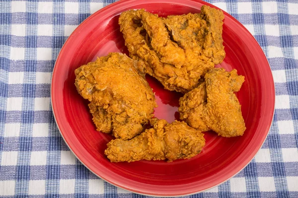 Cuatro piezas de pollo frito en la placa roja — Foto de Stock