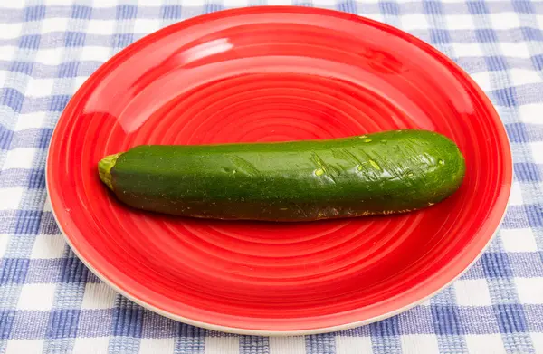 Grüne Zuchinni auf rotem Teller — Stockfoto