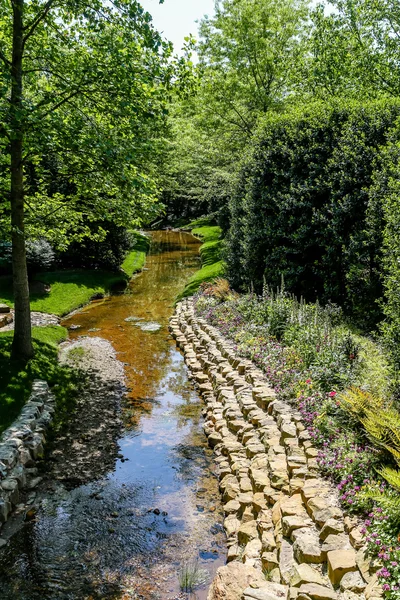 Каменный берег реки через сад — стоковое фото