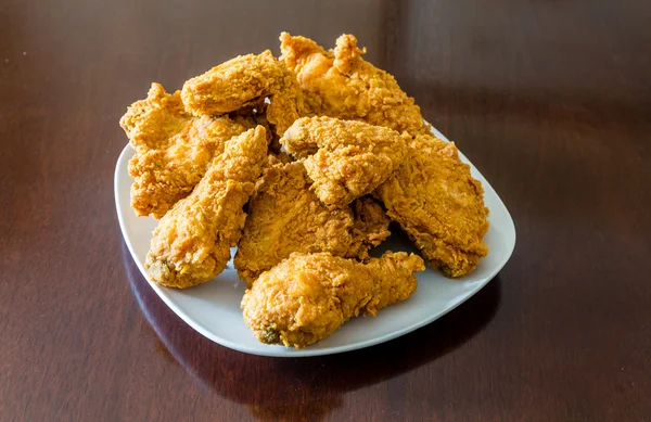 Жареный цыпленок в квадратной тарелке на полированном деревянном столе — стоковое фото