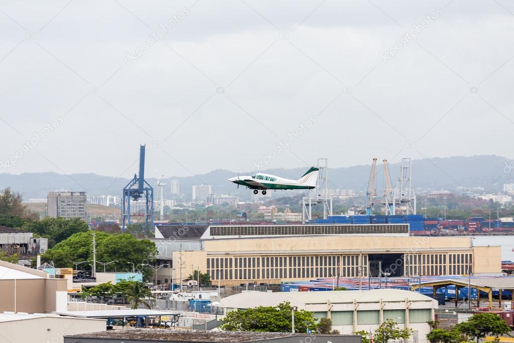 Green and White Plane Ascending Over Industrial Area