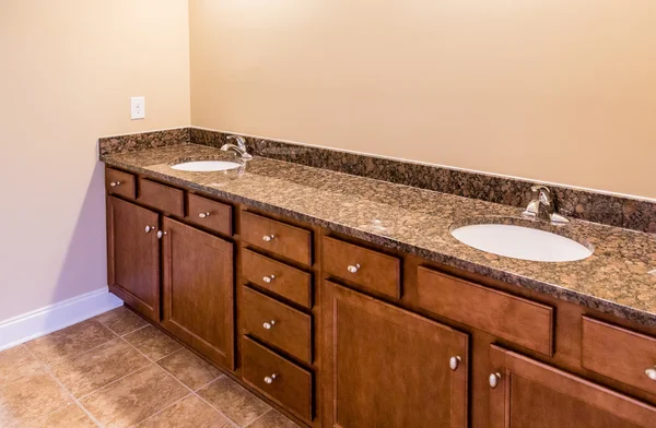 Szafki łazienkowe z granitową toaletką i podłogą wyłożoną kafelkami — Zdjęcie stockowe
