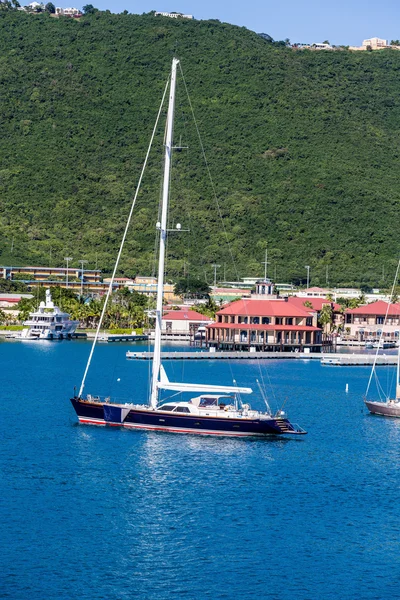 Blau-weißes Segelboot auf blauem Wasser bei grünen Hügeln — Stockfoto