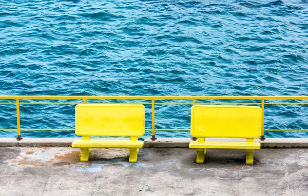 Gelbe Bänke am blauen Wasser — Stockfoto