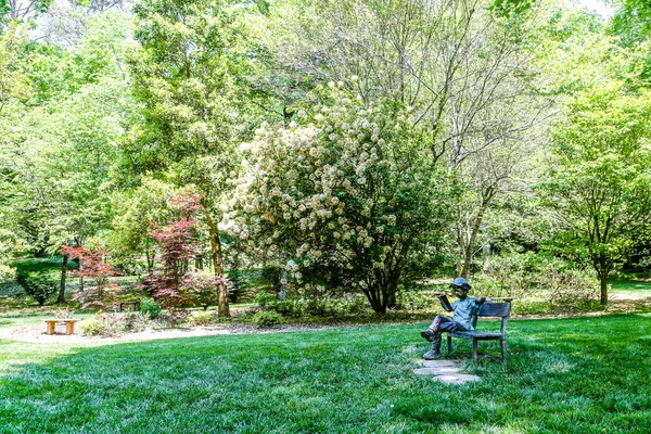 Jardin avec statue de garçon sur banc — Photo