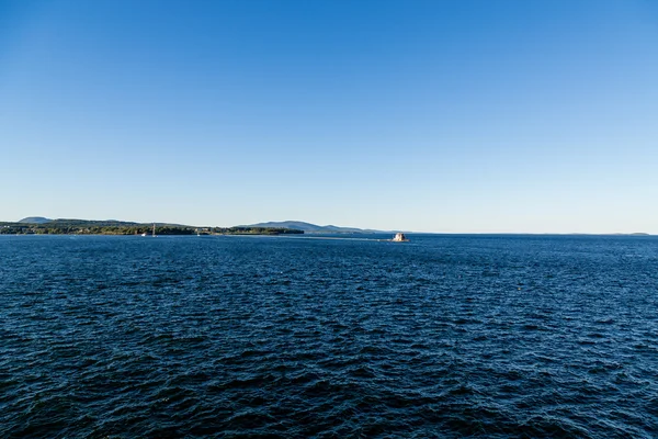 Blauwe zee voor de kust van Maine met vuurtoren in afstand — Stockfoto