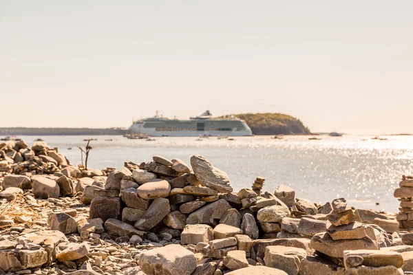 Výletní loď v dálce nad skládané kameny — Stock fotografie