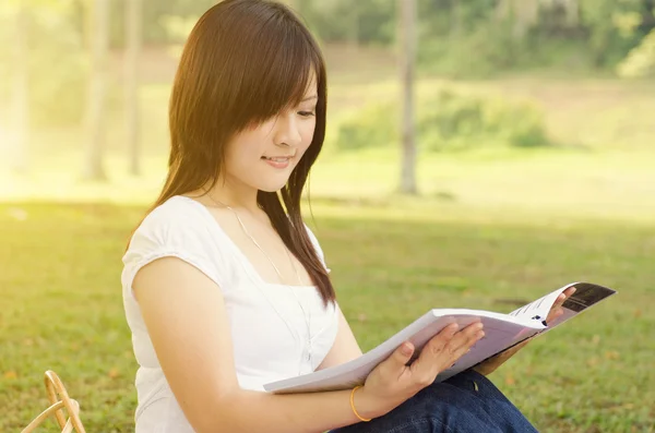 Young Asian college girl student reading book — Stock Photo, Image