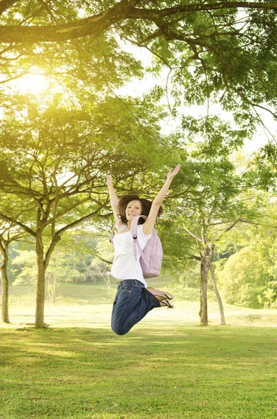 Unga asiatiska college flicka student öppna armar hoppning — Stockfoto