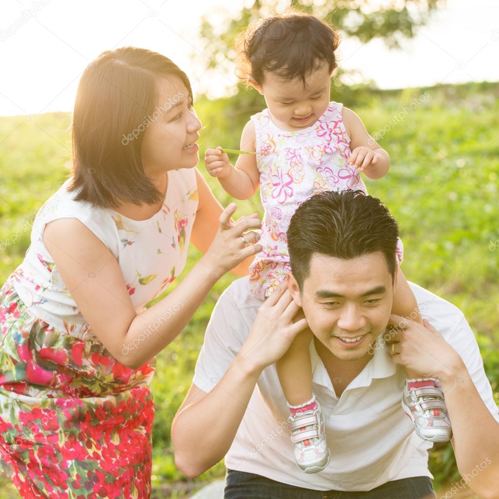 Asian family playing at outdoor park during sunset