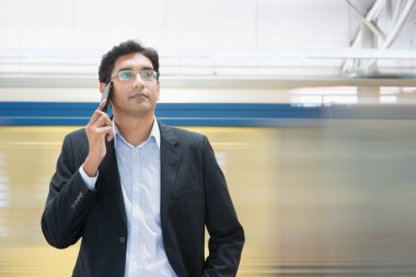 Tren istasyonunda telefonda konuşuyor