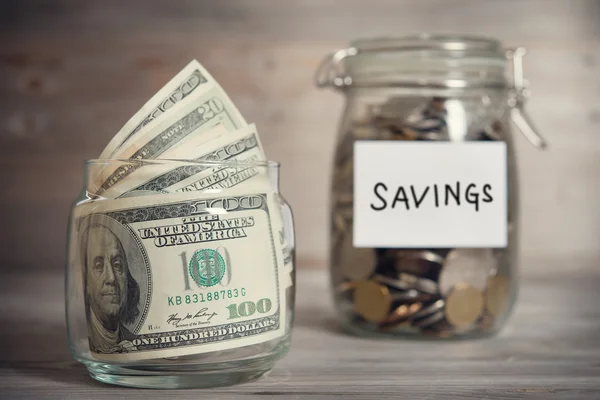 Dollars and coins in jar with saving label — Stock Photo, Image