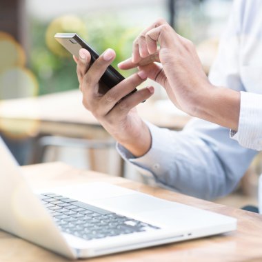 Smartphone ve dizüstü bilgisayar açık kullanan adam