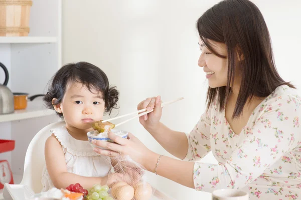 Asian mother feeding child — Stock Photo, Image