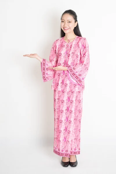 Asiatique fille en rose robe batik montrant quelquechose — Photo