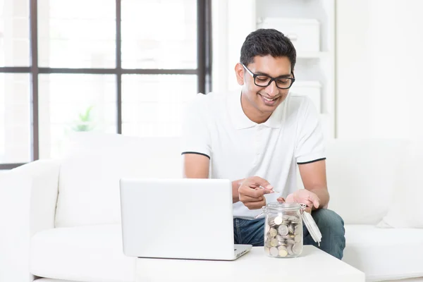 Chico indio usando la computadora y contando dinero en casa —  Fotos de Stock