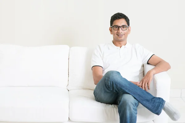 Gut aussehende junge indische Kerl sitzt auf Sofa — Stockfoto