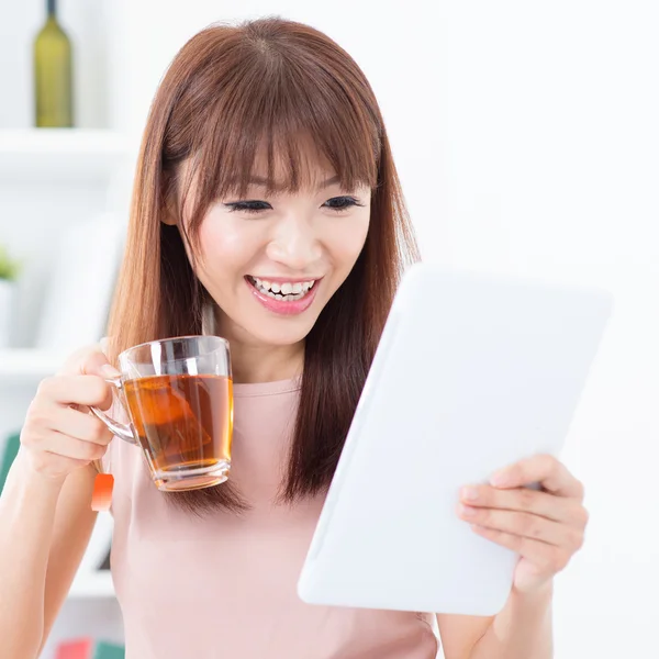 Chica asiática tomando té mientras usa la tableta — Foto de Stock