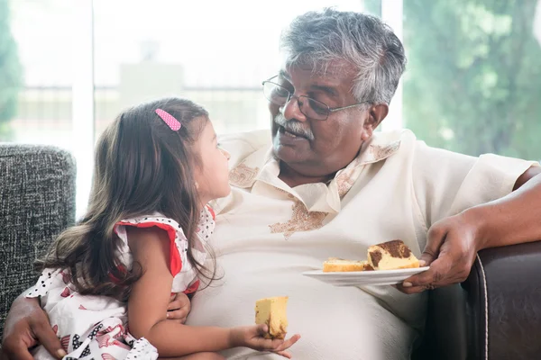 Granddaughter and grandfather eating cake — Stock Photo, Image