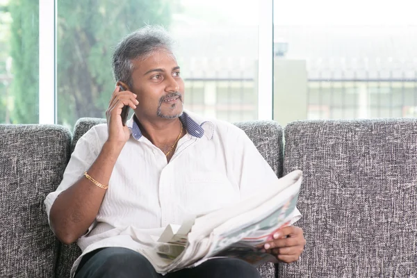 Indian man reading newspaper and calling phone — Stock Photo, Image