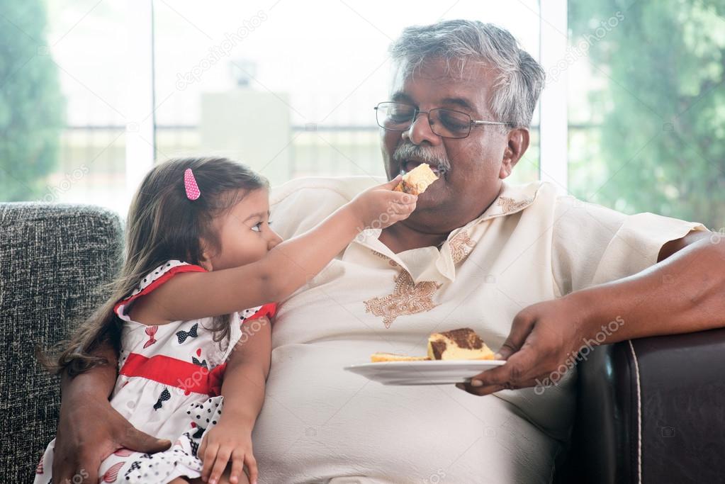 Granddaughter feeding grandfather cake