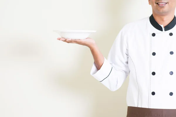 Índio masculino chef no uniforme segurando um vazio prato — Fotografia de Stock