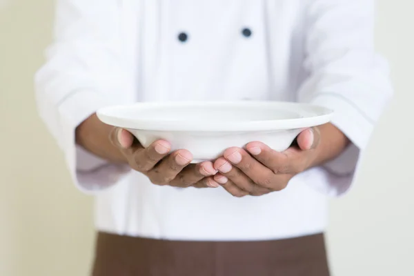 Индийский шеф-повар в форме представляет пустую тарелку — стоковое фото