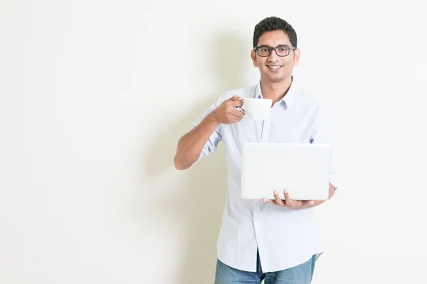 Casual business Indian male using computer and drinking tea — Stockfoto