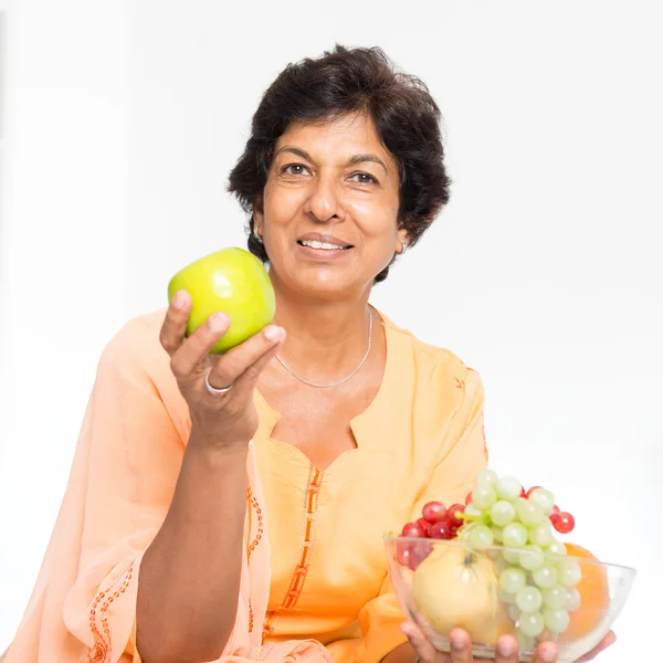 Indian mature woman eating fruits — Stok fotoğraf