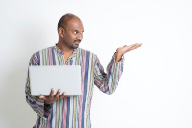 Mature casual Indian man using computer and showing something