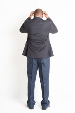 Back side full length mature Indian businessman thinking