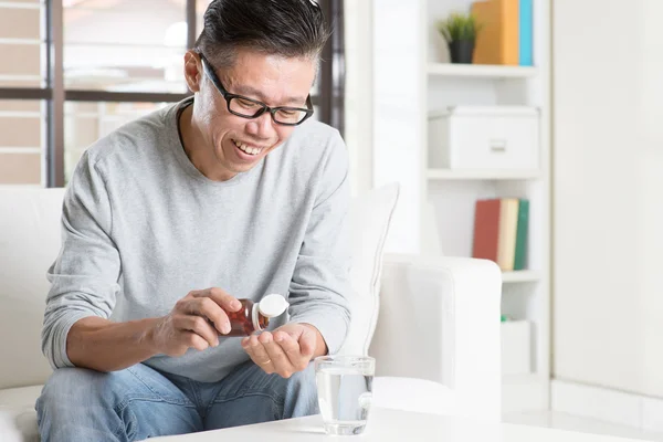 Asian man eating supplement — Stock Photo, Image