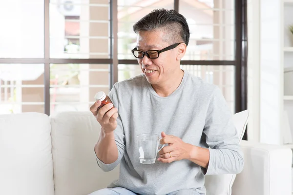 Asian man eating vitamins — Stock Photo, Image