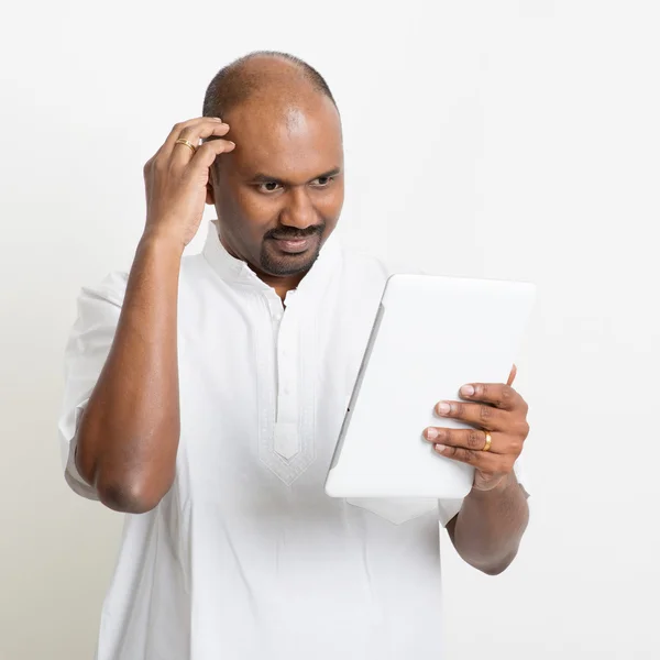 Mature casual business Indian man using tablet pc and scratching — Stock fotografie