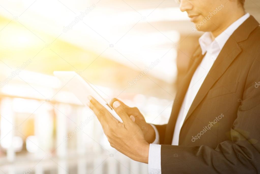 Businessman using tablet computer at train station