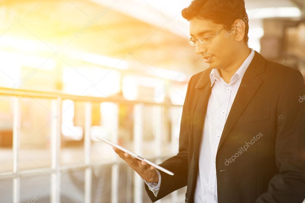 Indian Businessman using tablet computer at train station