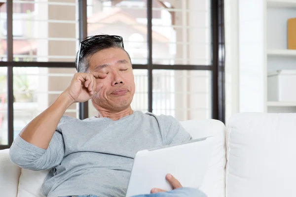 Mature Asian man eyes pain while using tablet computer — Stok fotoğraf